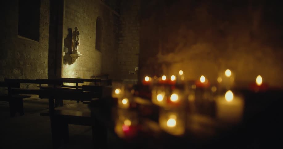 Candles burning next to pews in a church