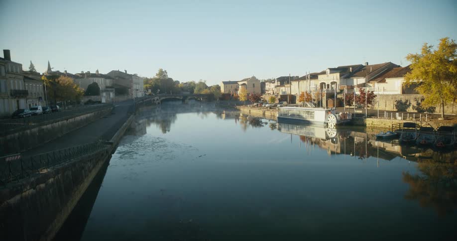 Stone bridge crosses over river between apartment buildings