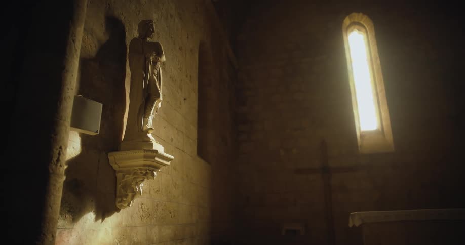 Statue over a pedestal on the wall of a dimly lit church