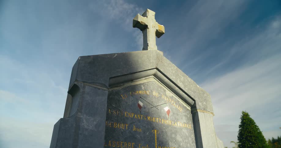 A large tombstone under a blue daytime sky