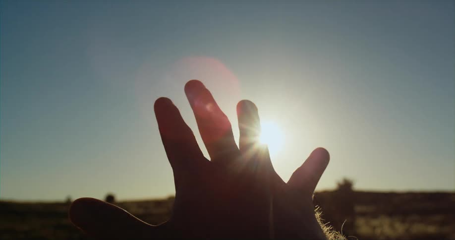 A close up of a mans hand as he moves across the suns reflection