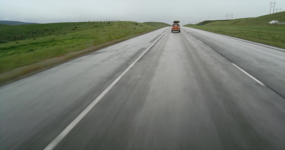 A volkswagen beetle traveling on an empty road