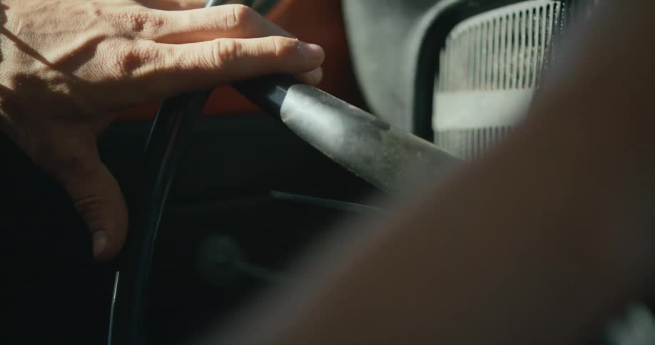 Close up of a mans hand as he steers a steering wheel in a car