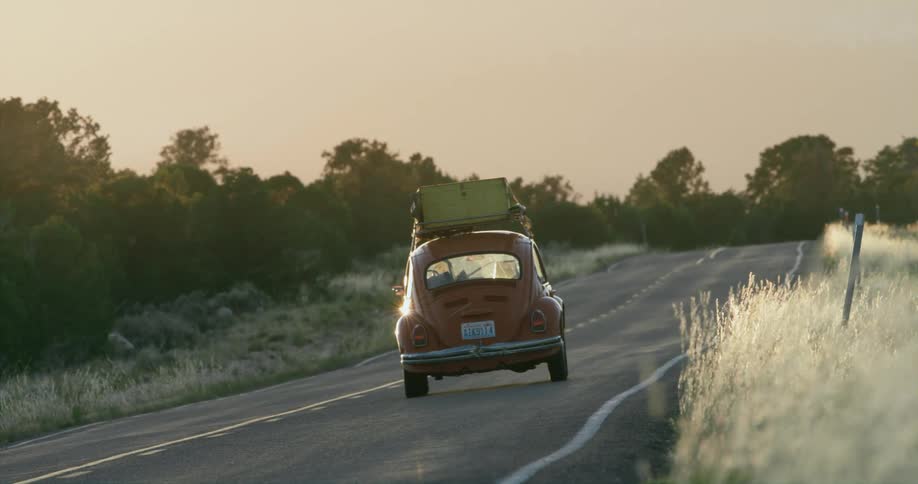 A car travels along a road through the countryside in the evening