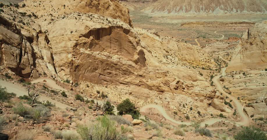 Car drives on a dirt road mountain pass on the badlands through the desert