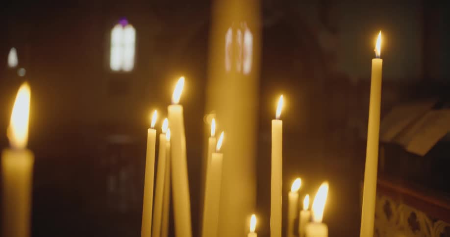 Several candles burn in large church illuminating the dim interior