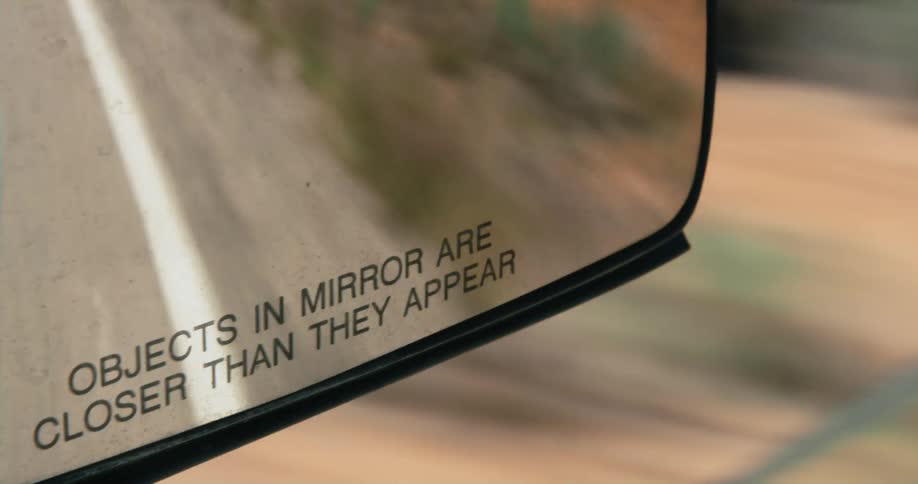 Close up of the text on the base of a rear view mirror in a vehicle driving on the road