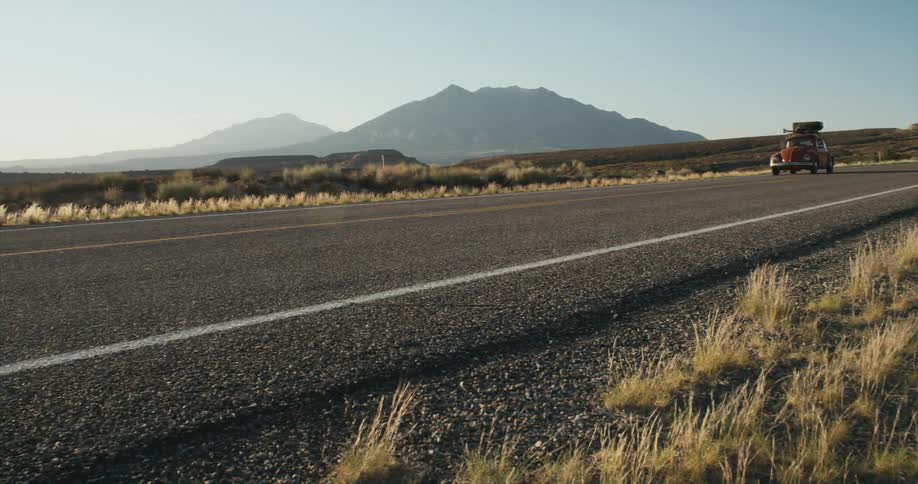 A car travels along a road through the countryside during the day