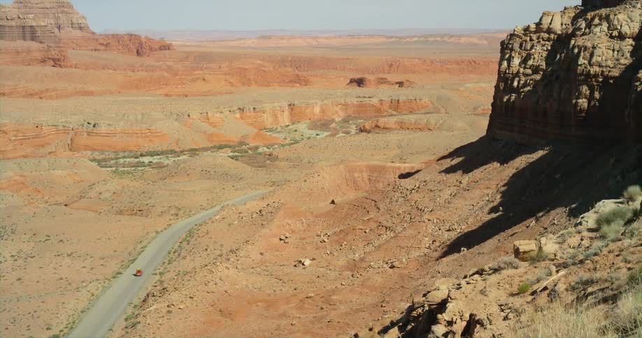 Red car drives on a road through the badlands