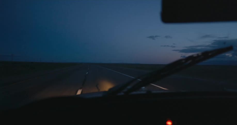 A car is diving on a road in a rural area at night