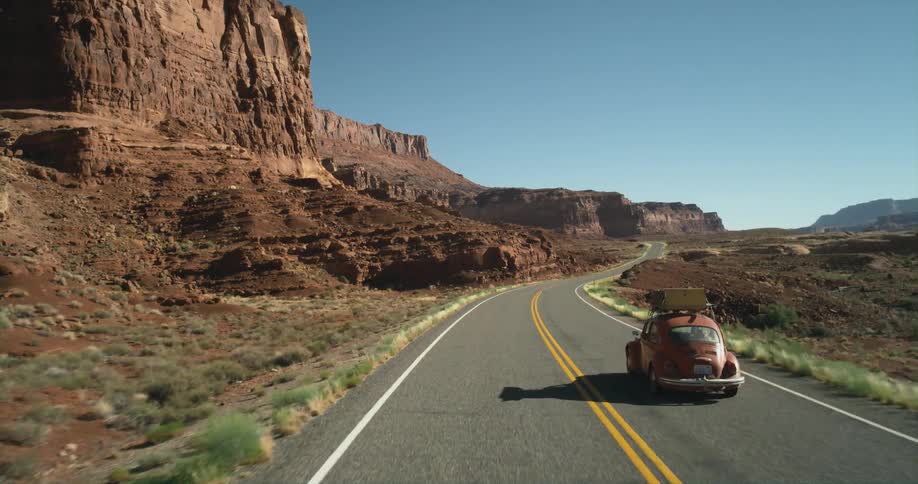 A car drives down a street past a canyon