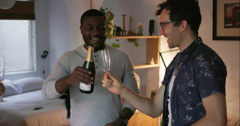 A man raises a bottle to a toast with friends then pours some