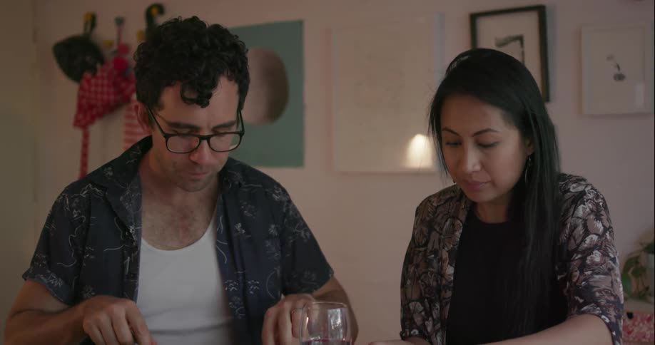 A couple of people sitting at a table in their home eating food