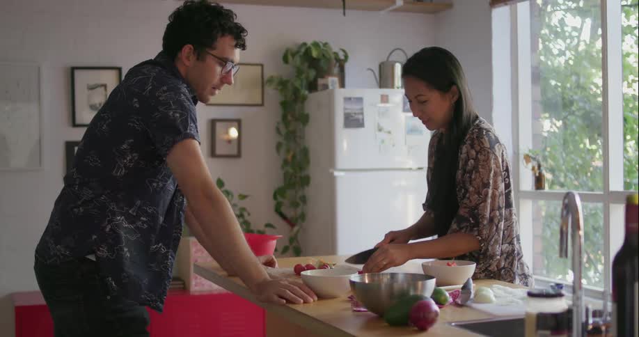Man and woman chop food on a kitchen counter
