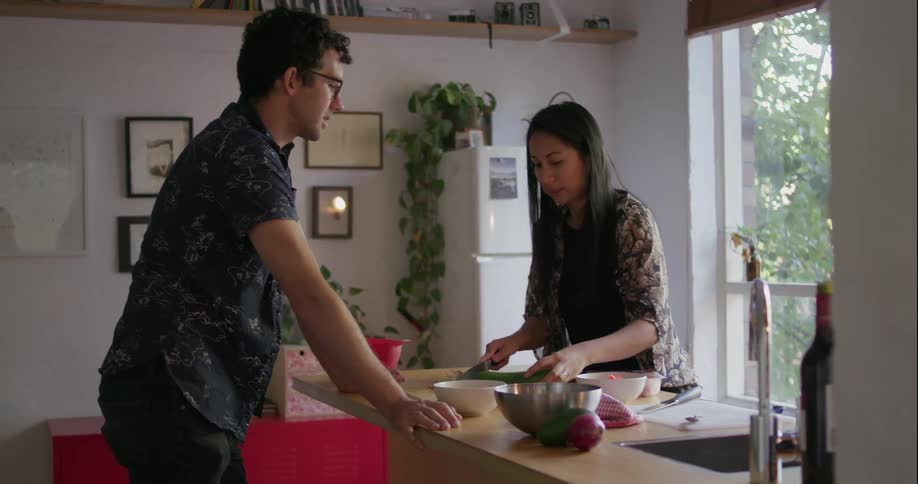 A man talks with a woman as she is cooking