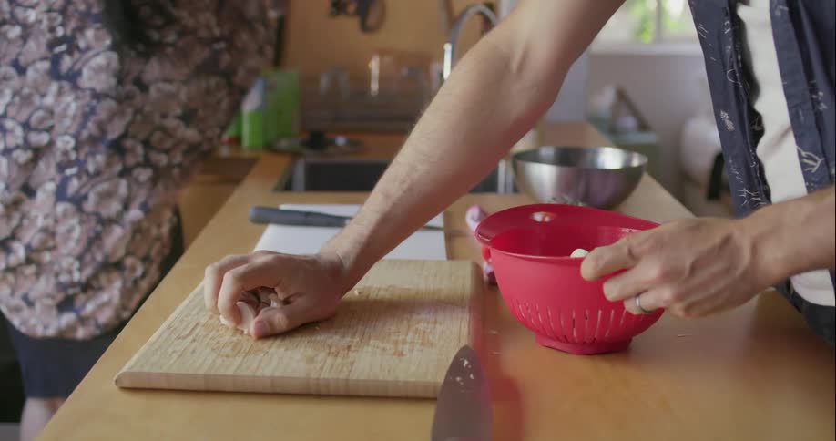 A man puts diced mushrooms in a bowl