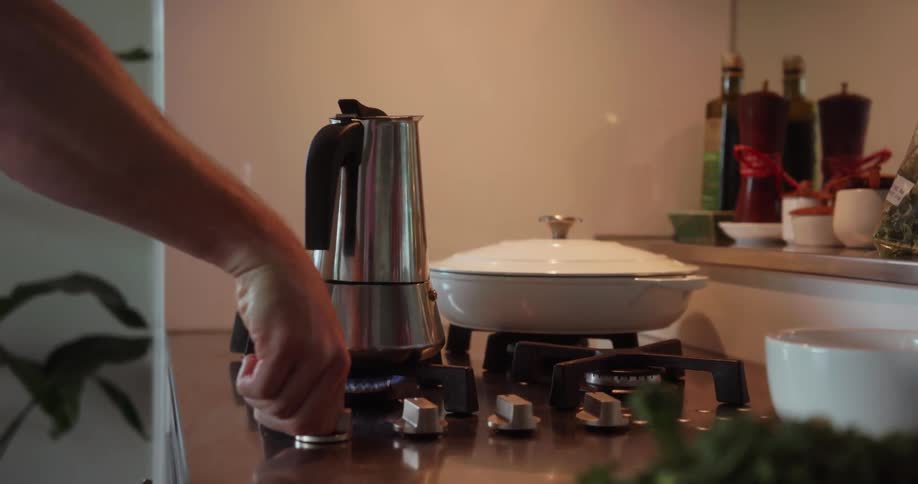 A man puts a tea kettle on the stove