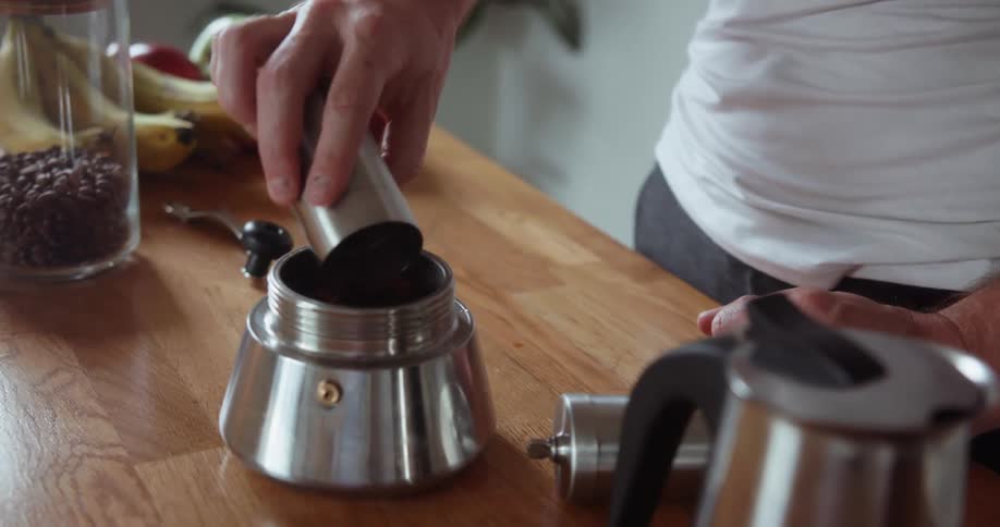 A man pours coffee grounds into a canister
