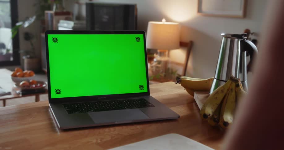 A man picks up a coffee mug near his laptop