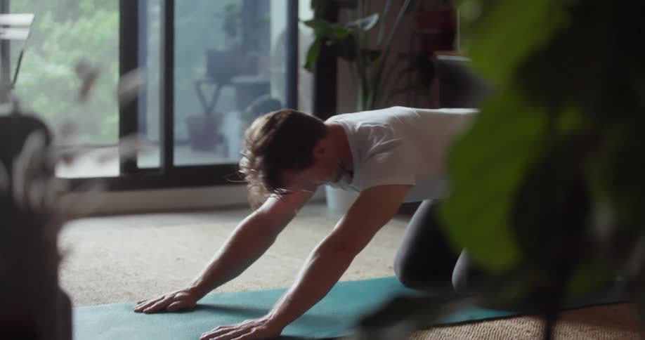Man practices yoga in his living room
