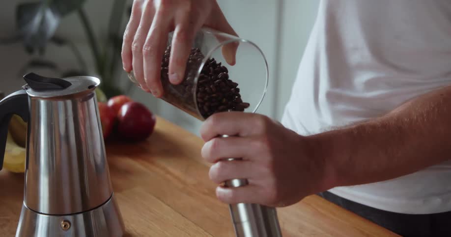 A man pours some coffee beans into a container