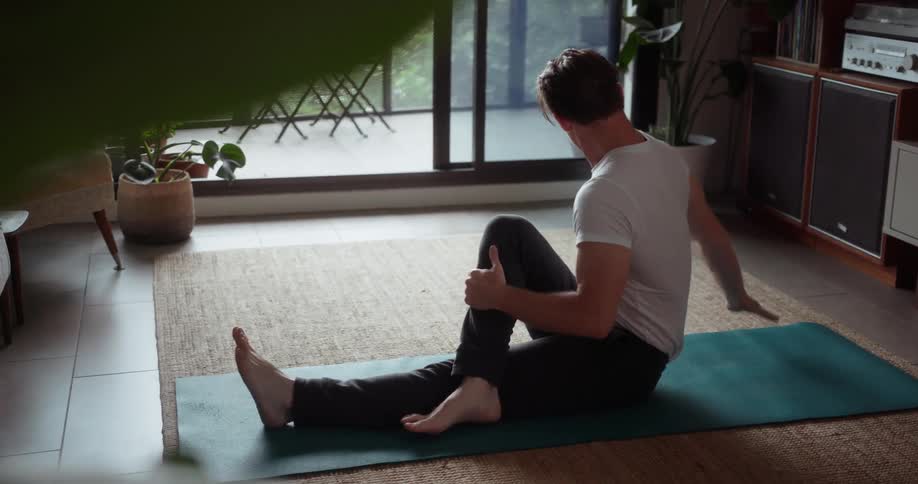 A man is doing different yoga poses in his home