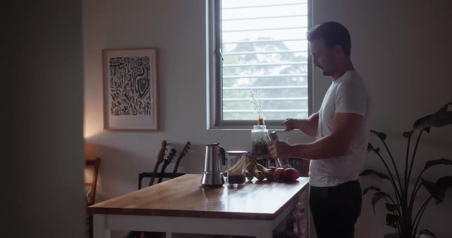 A man is using a grinder in a kitchen at dawn