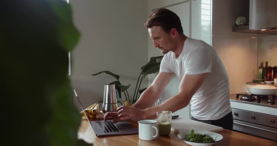 A man uses a laptop in the kitchen