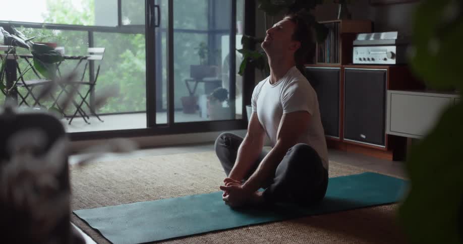 Man practices yoga in his living room