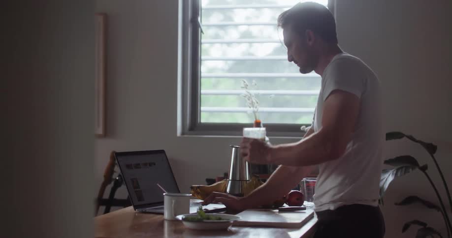 A man uses a laptop in the kitchen