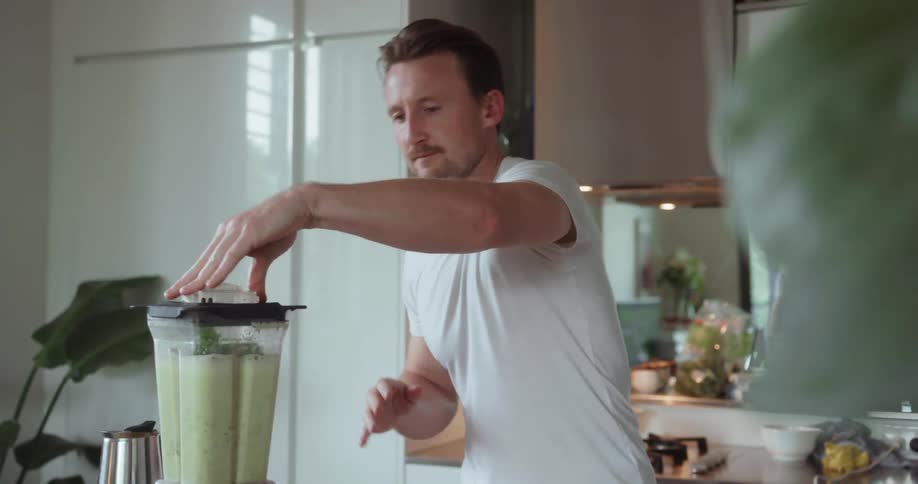 A man uses the blender to make himself a shake