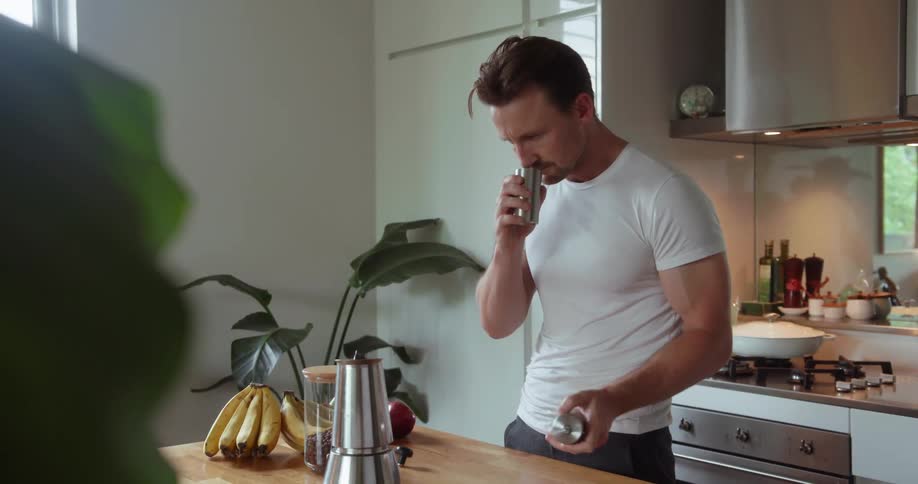 A man opens the hand grinder and smells the coffee
