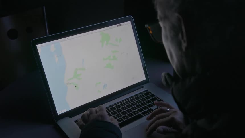 A man is scrolling a map on his laptop