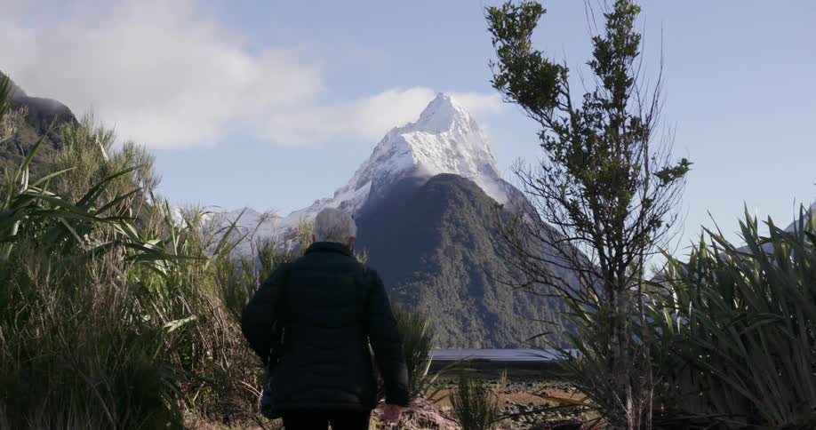 A woman in a puffer jacket walks up a trail