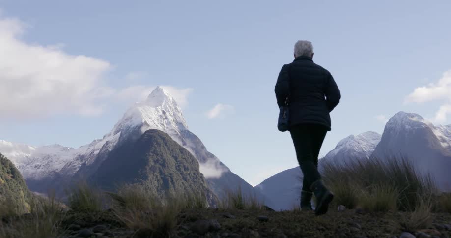 A person walks uphill to view a mountain range