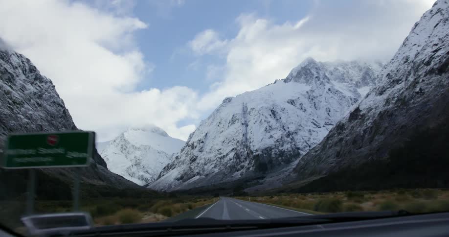 A car drives towards snow covered mountains