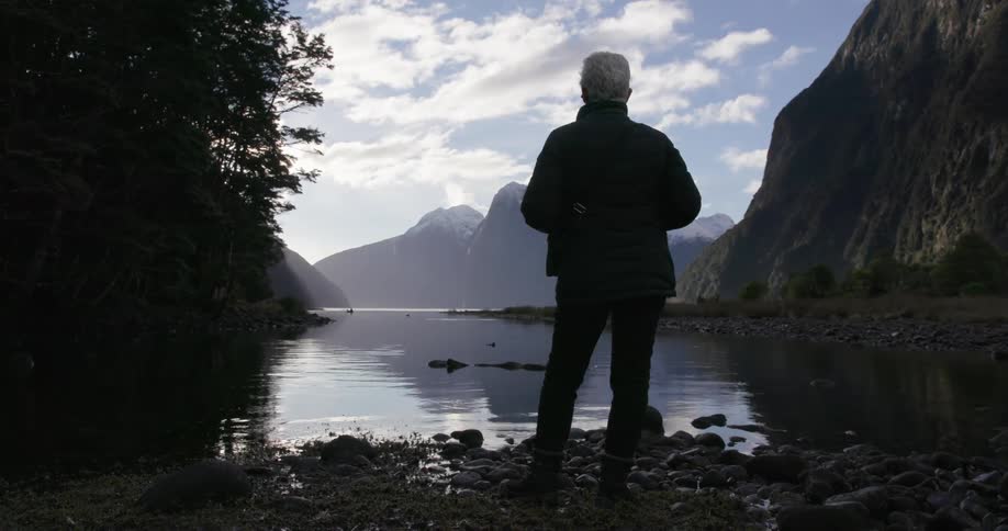 A woman stands on a rocky shore in New Zealand