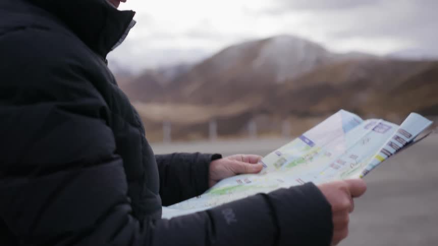 Woman looks at a map outside near mountains on a windy day