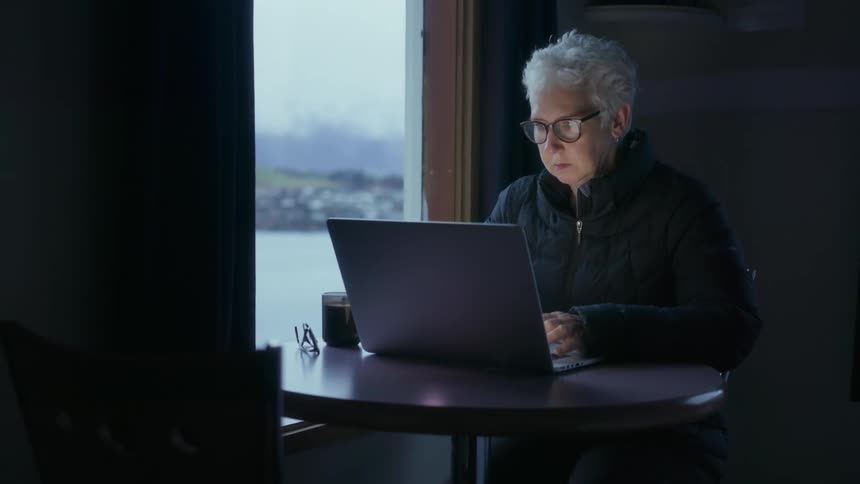 A woman is using her laptop in a dark room