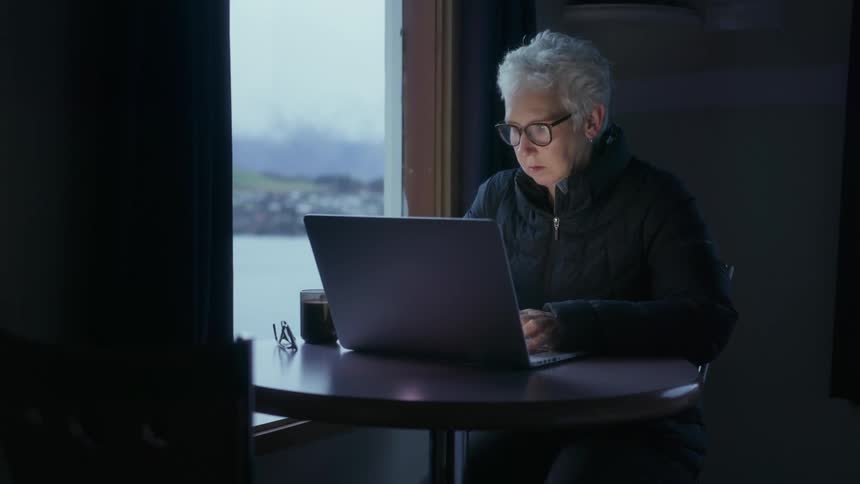 A woman wearing glasses is using her laptop