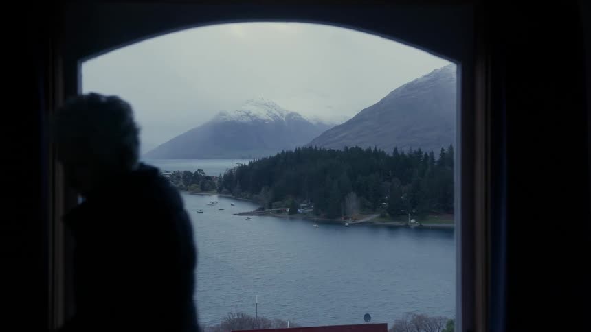 A person walks over and opens the curtain to the window