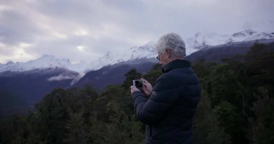 A woman takes a picture of trees with her phone