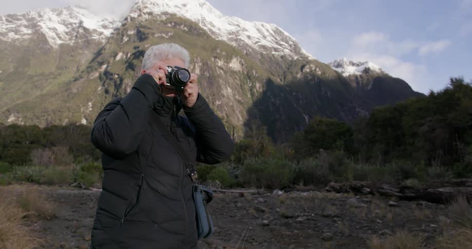 A woman takes pictures near a mountain