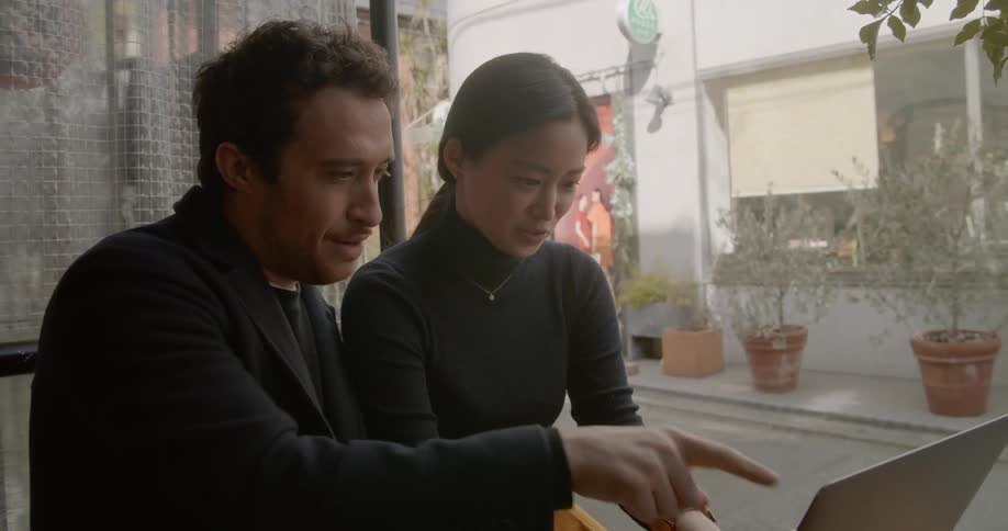 Man and woman at table with coffee talk and work on laptop