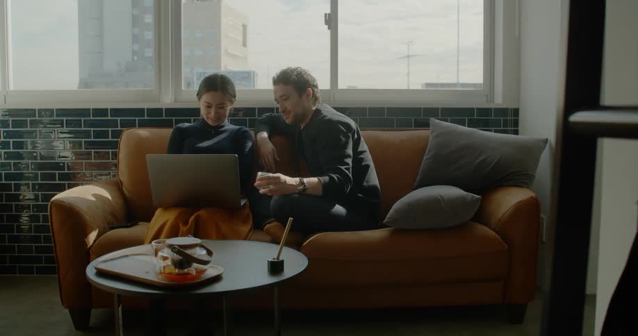 Couple sitting in couch on living room using a laptop