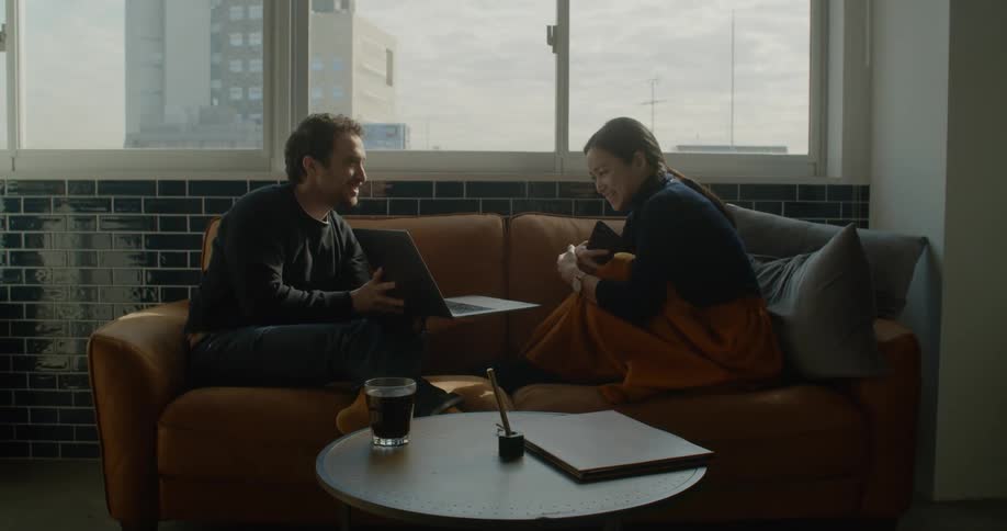 Man and women sit on couch discussing laptop content