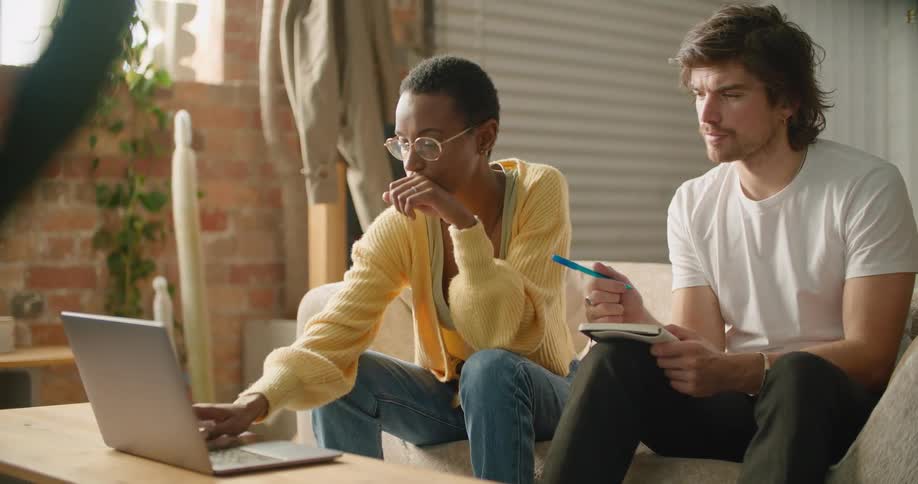 A man and woman look at a computer and talk