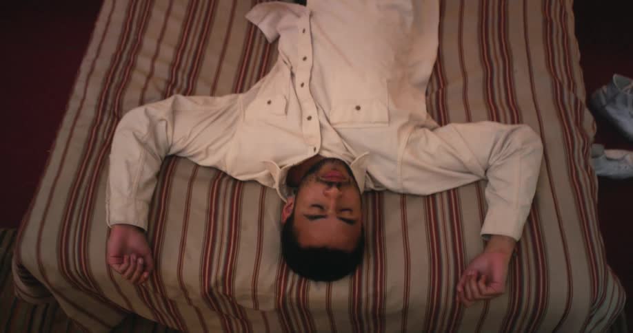 A bed lies down fully dressed on a striped comforter in bed