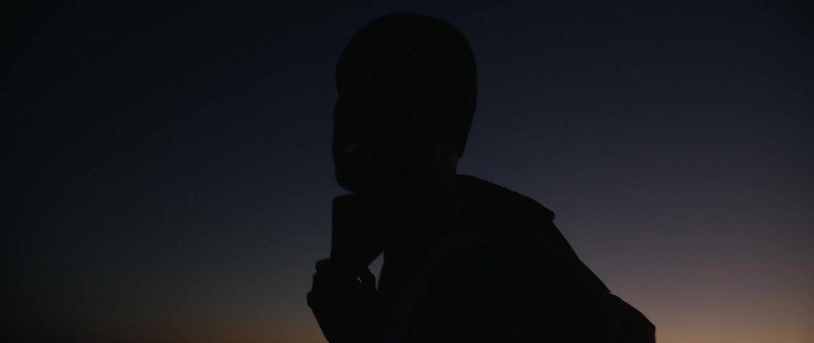 A silhouette of a man is outside at dusk