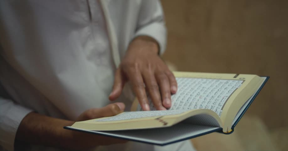 Young man is reading a book outdoors in the daytime
